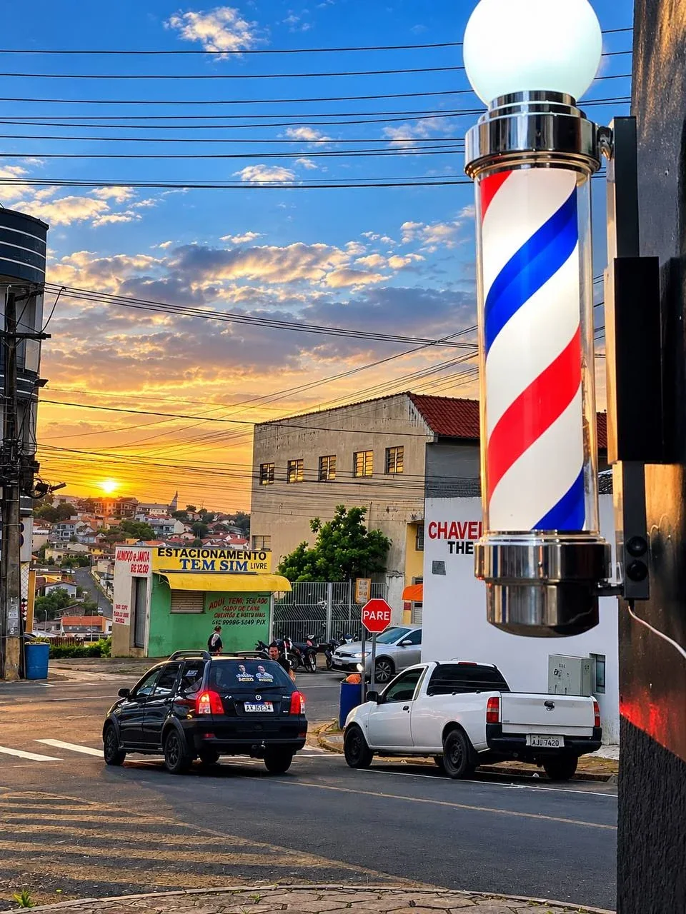 Poste de barbeiro da Navalha aceso ao pôr do sol, em frente ao Tem Sim Lanches